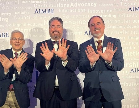 three men make the owl sign at the camera