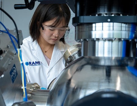 female researcher wearing lab coat operating large instrument
