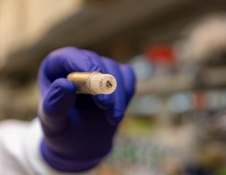 gloved hand holding a small device