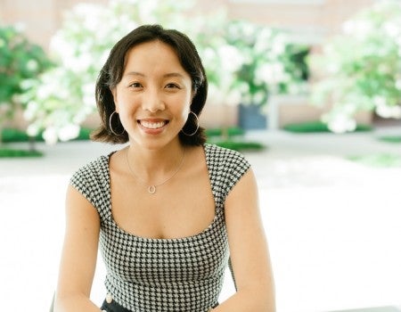 Lily Lee, sitting outside in front of green trees. 