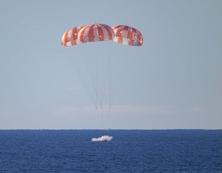 NASA's Orion spacecraft landing in the ocean: three striped parachutes landing on blue water