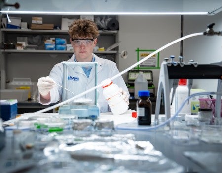 Simon M. King, a sophomore studying chemical and biomolecular engineering and first author of the study, in a white lab coat doing an experiment. 