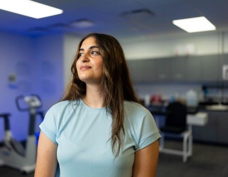 A Latina woman with long wavy brown hair looks upward with a slight smile