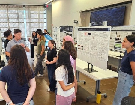 poster presentation session with students listening to a presenter