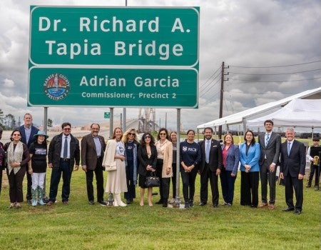 A group of people stand under a sign that reads Dr. Richard A. Tapia Bridge