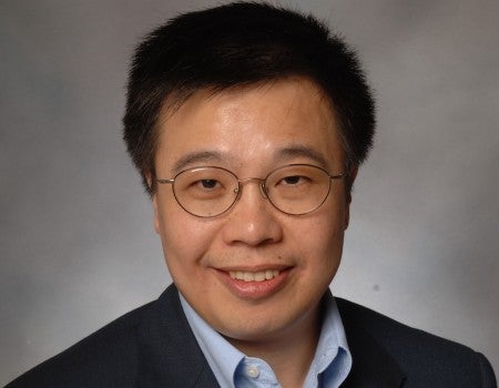 A Chinese man in glasses smiles at the camera