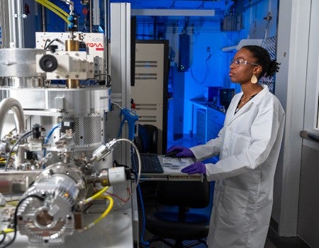 black female researcher in lab coat interacts with research equipment