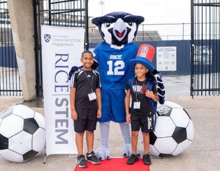 Two campers stand next to Sammy the Owl outside Rice Stadium