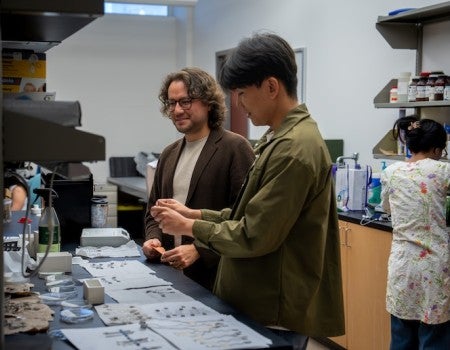 Two researchers working at the lab bench and talking.