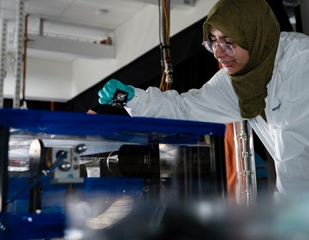researcher in lab coat interacting with equipment