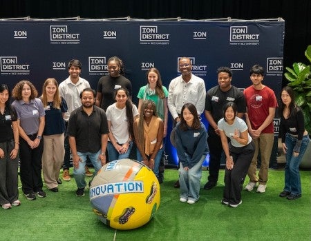 A group of people gather around a large soccer ball. 