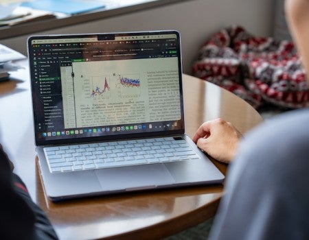 A computer screen shows graphs, with two people looking at them. 