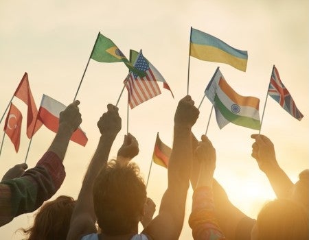 People waving international flags at sunrise. 