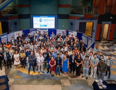 A large group of people stands in front of posters