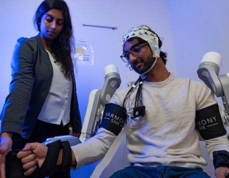 Keya Ghonasgi and Snehil Mathur, a graduate student in Mechanical Engineering, demonstrating how the exoskeleton functions 
