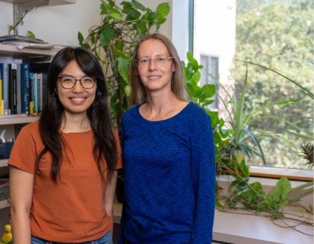 An Asian woman stands next to a white woman. 
