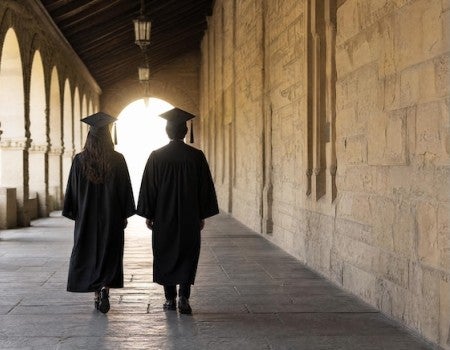 Stock image of two people in graduation caps and gowns walking