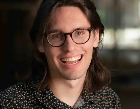 A young white man smiles at the camera