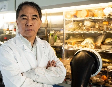 An Asian man in a lab looks at the camera
