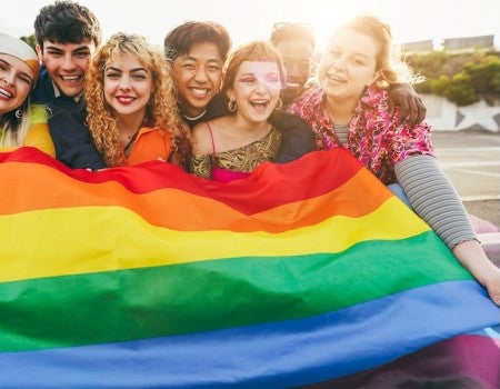 A group holds a Pride flag.