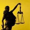 Figure of Justice holding scales over a yellow background with copy space in a conceptual image