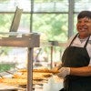 A housing and dining worker serves food after Hurricane Beryl.