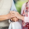 Photo of caregiver and loved one holding hands.
