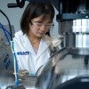 female researcher wearing lab coat operating large instrument