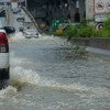 A truck drives through a flooded road, following a line of cars onto an elevated on-ramp