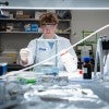 Simon M. King, a sophomore studying chemical and biomolecular engineering and first author of the study, in a white lab coat doing an experiment. 