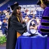 student in academic robes receives ring from professor 