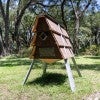 A small triangular prism on stilt legs leans gently to the right 