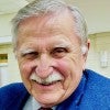 An older white man grins at the camera 