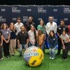 A group of people gather around a large soccer ball.  