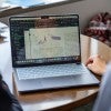 A computer screen shows graphs, with two people looking at them. 