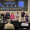 A group of people stand in front of an audience, talking and laughing.  