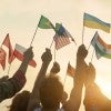 People waving international flags at sunrise. 