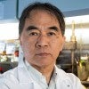 An Asian man in a lab stares at the camera 
