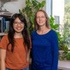 An Asian woman stands next to a white woman.  