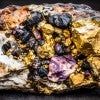 Raw rare earth mineral crystals on the weathered crust of yellow brown granite 
