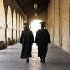 Stock image of two people in graduation caps and gowns walking