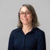A white woman in glasses smiles at the camera 